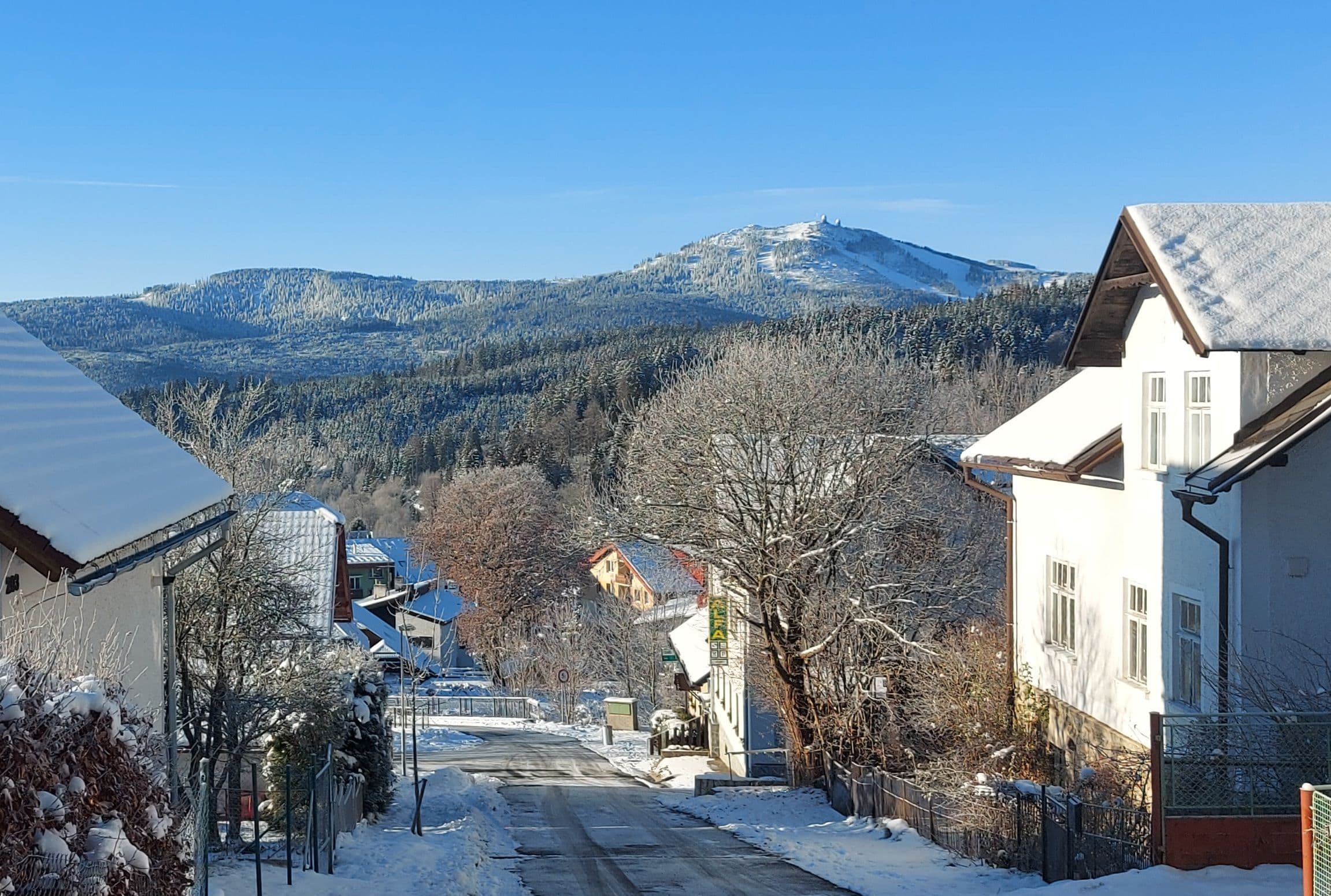Winter street in Železná Ruda facing a snowy mountain