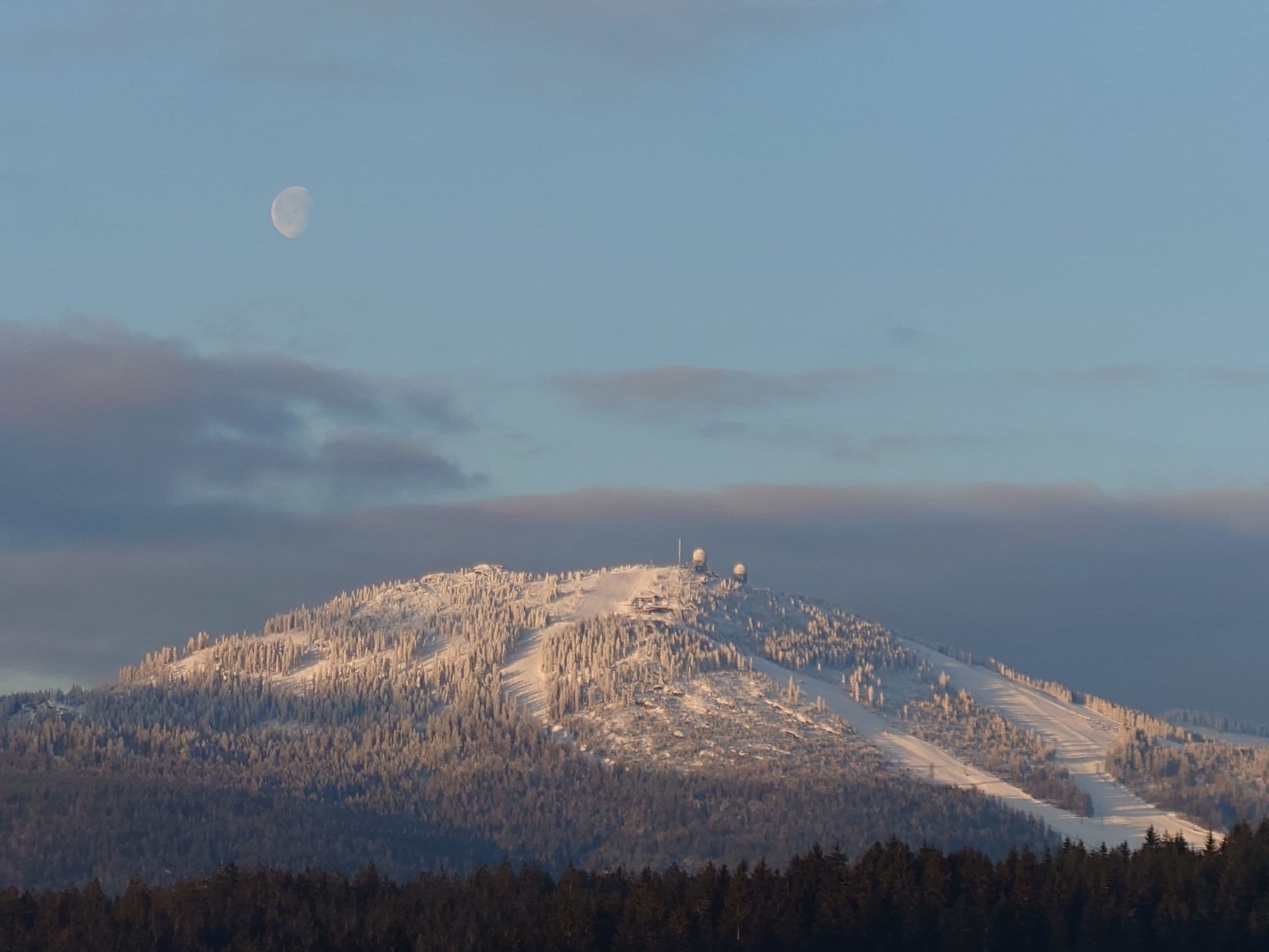 Snow-covered Pancíř peak with ski slopes at dawn